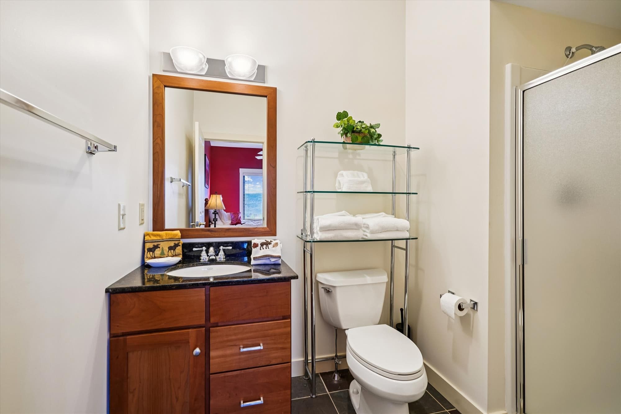 Clean and modern bath with walk-in shower, granite vanity, and open shelving. Easily accessible from the queen bedroom.
