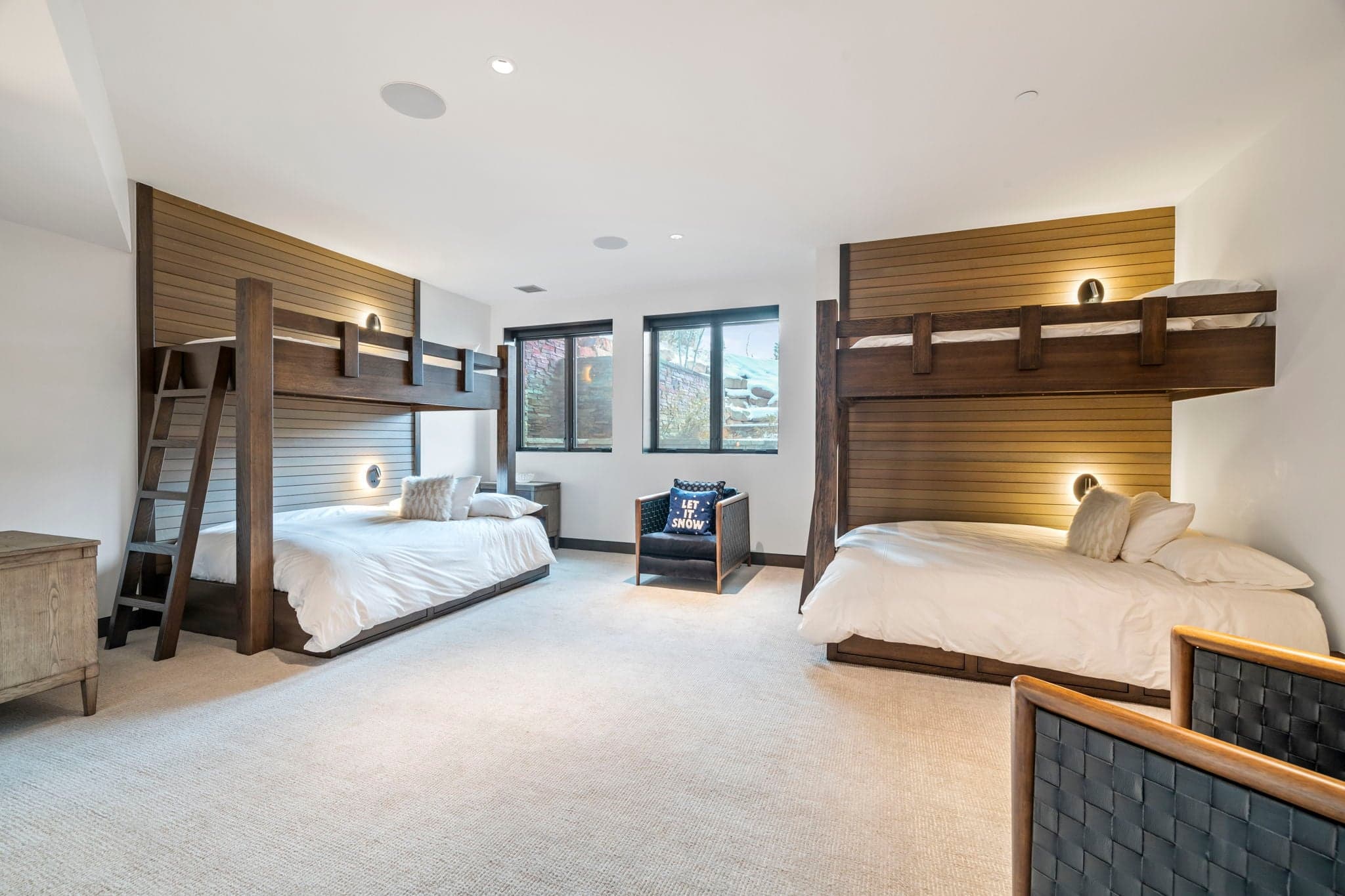 A large bedroom with two bunk beds and chairs.